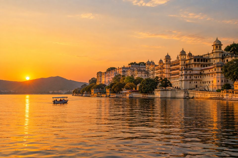 Sunset over Lake Pichola in Udaipur with a small boat on the water and City Palace glowing along the shore